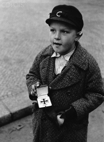 Berlin, 1945 German boy tries to sell his father's Iron Cross for cigarettes.