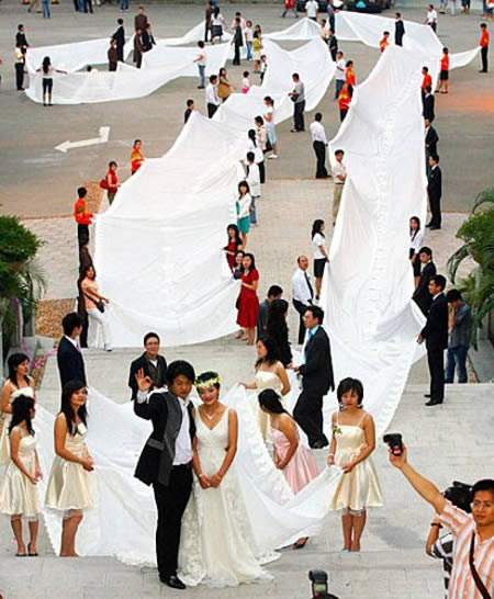 The Chinese bride who wore a 200m-long dress to set a World record:
The bride from Guangzhou, China, set the world's longest bridal train record at 219 yards. The Chinese bride accented her gown with a train that was over 600 ft long and weighed over 220 lbs. Xie Qiyun had this photos taken in front of a hotel in Guangzhou, the capital of Guangdong Province on her special day. According to Guinness, the longest wedding dress train measured 1362 m [4468 ft 5.94 in] and was created by Andreas Evstratiou in Paphos, Cyprus, in February 2007.