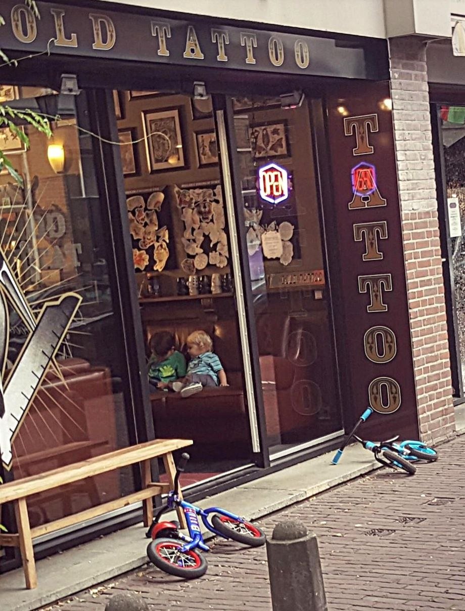 Kids on their bikes that are checking out tattoos at the local shop
