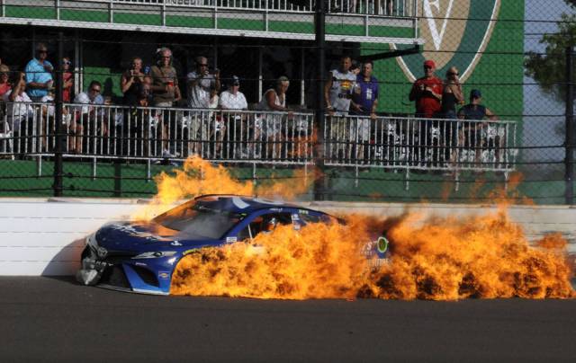 Racecar cruising by the crowd while on fire