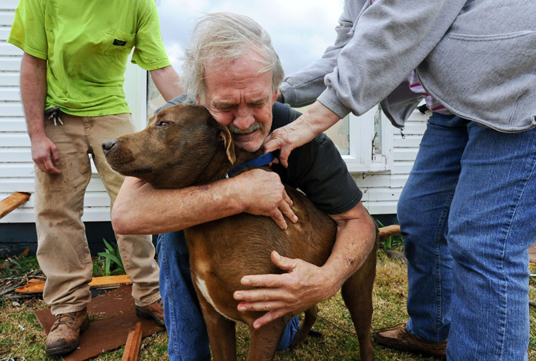 Greg Cook hugs his dog Coco after finding her inside his destroyed home in Alabama