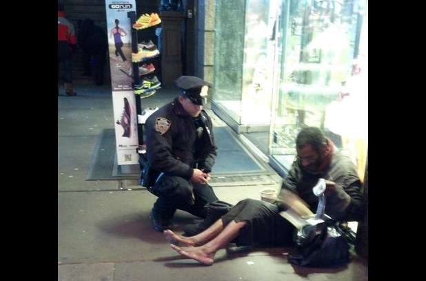 A tourist captured picture of an NYPD officer offering a homeless man a pair of all-weather boots and thermal socks on a frigid night.