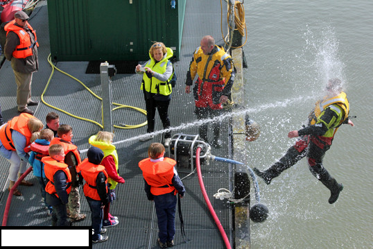 kids playing with water hose during coast guard demonstration