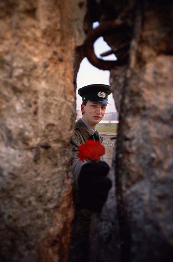 1989 - East German soldier passing a flower through the Berlin Wall before it was torn down