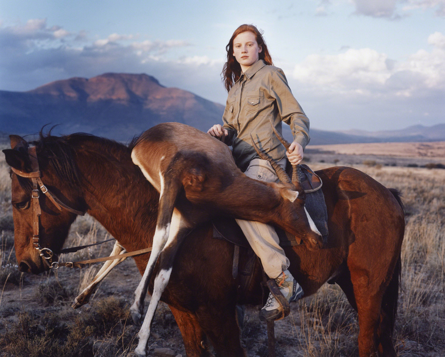 Girl on horseback with her trophy of a hunted dead buck.