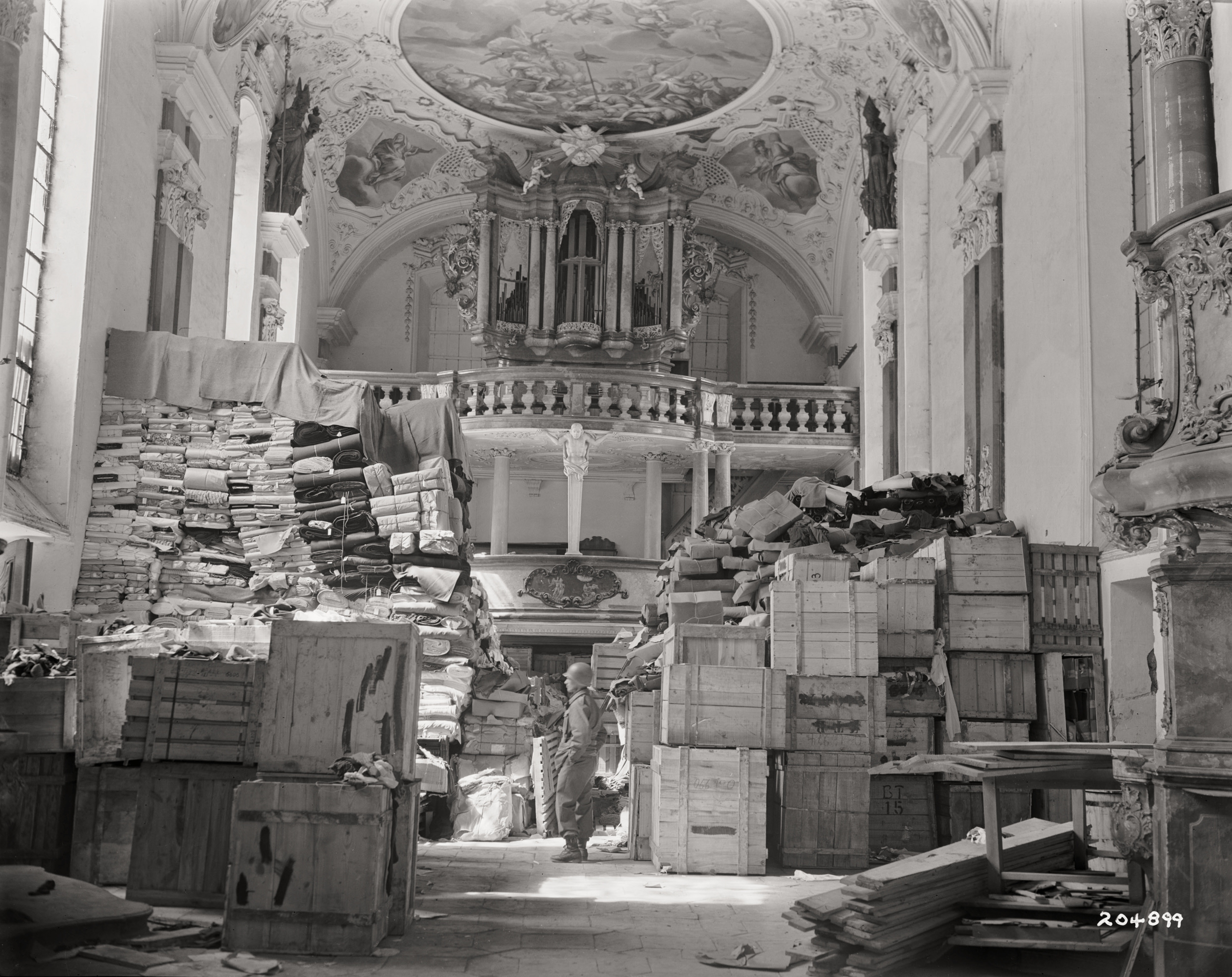 American soldier inspects German loot stored in a church at Elligen, Germany, April 24, 1945