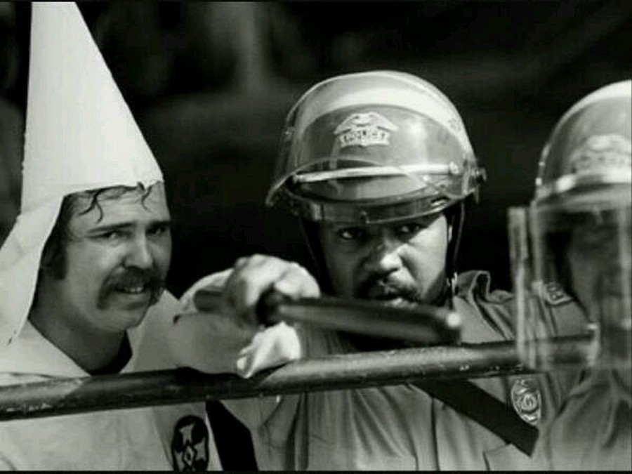 Black officer protecting KKK member from protesters, 1983.
