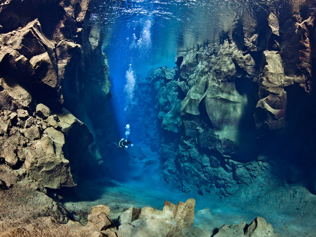 A diver swimming between two tectonic plates in Iceland.