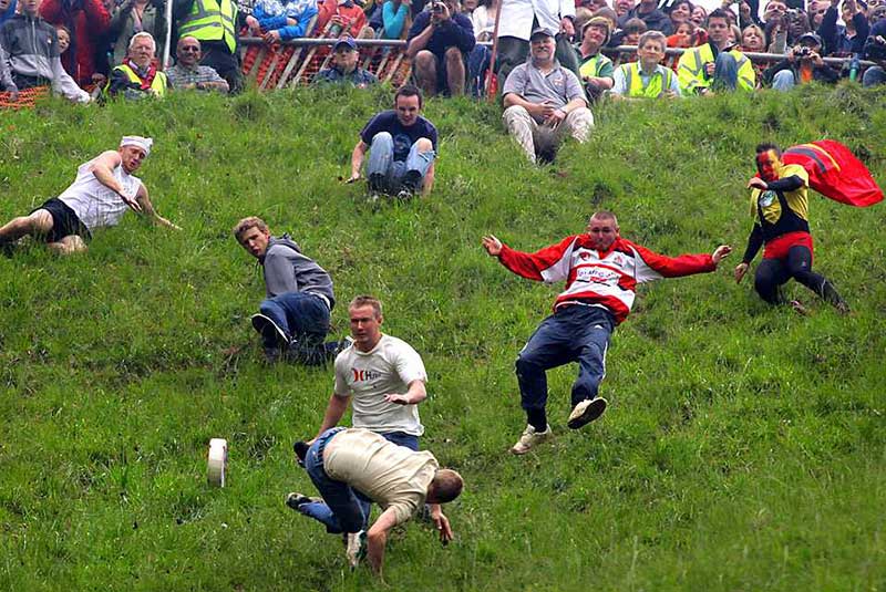 Cheese Rolling-A team roll a wooden ‘cheese’ during the Stilton Village Festival cheese rolling competition on May 5, 2014 in Stilton, England. The Stilton annual cheese rolling competition, which is held every May involves teams of four competing against each other by rolling cheese down the High Street to be crowned the ‘Stilton Cheese Rolling Champions’.