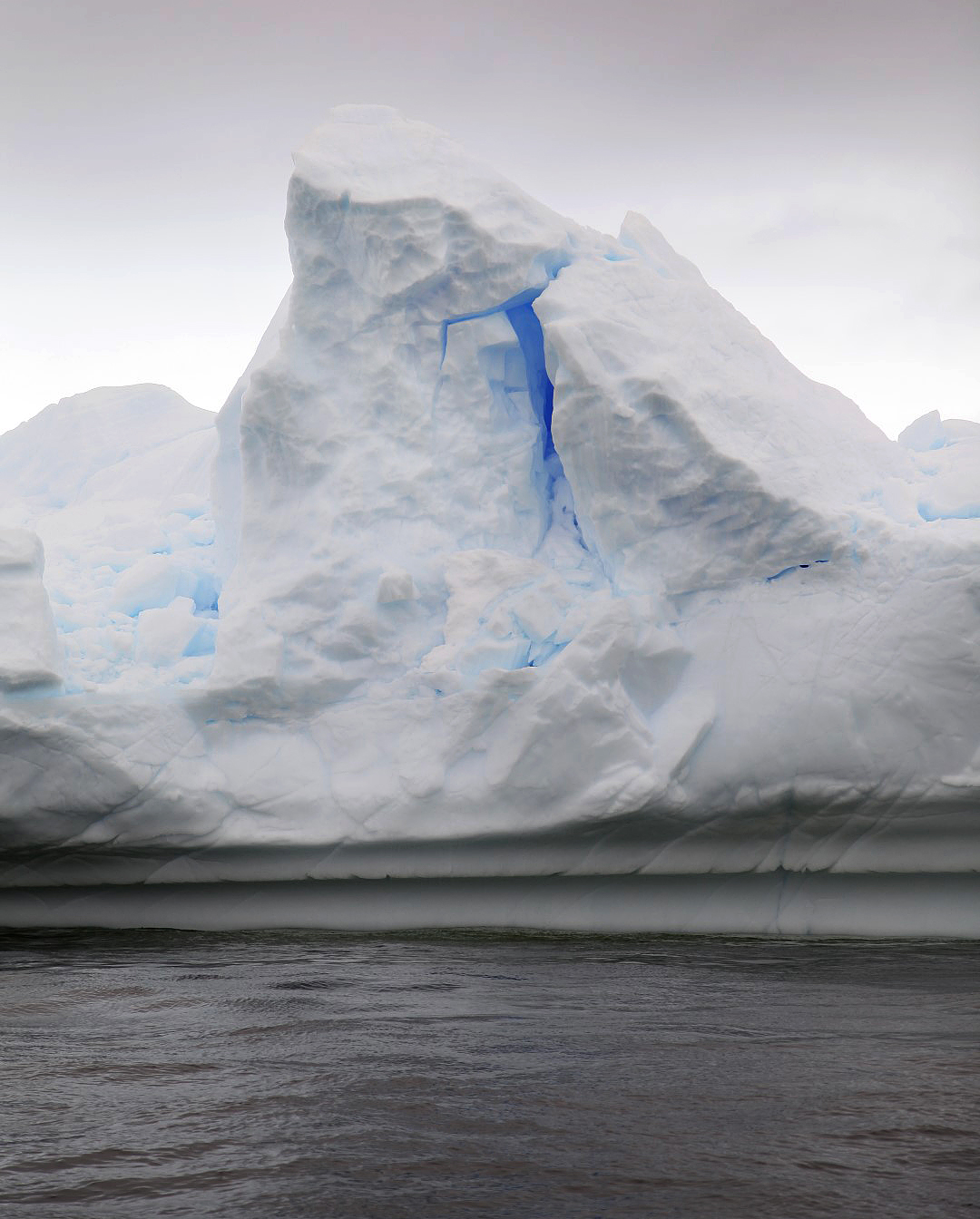 A bright, brillant blue glows from within an Antarctic iceberg