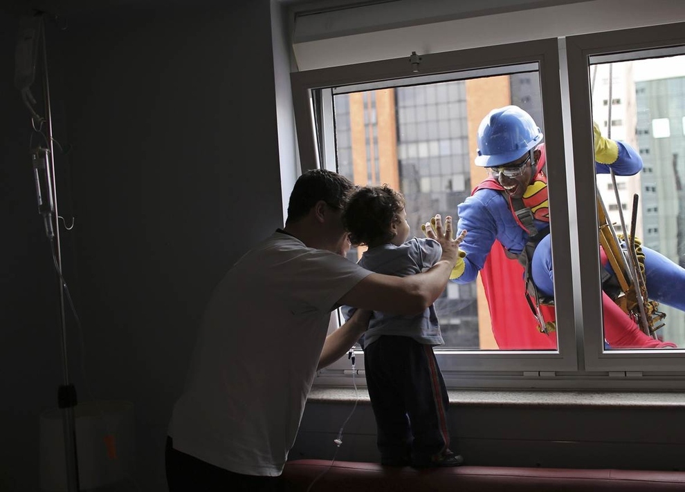 A man dressed as Superman smiles at patient Joao Bertola, 2, and his father at the Hospital Infantil Sabara in Sao Paulo, Brazil.