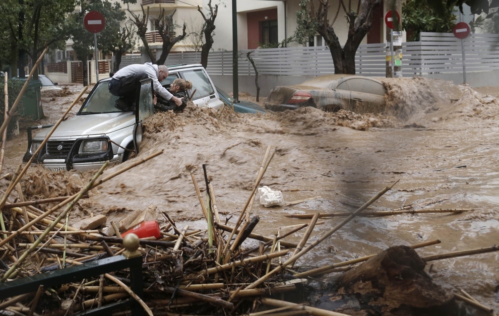 A man rescues a woman from her car on a flooded road in the Athens suburb of Chalandri