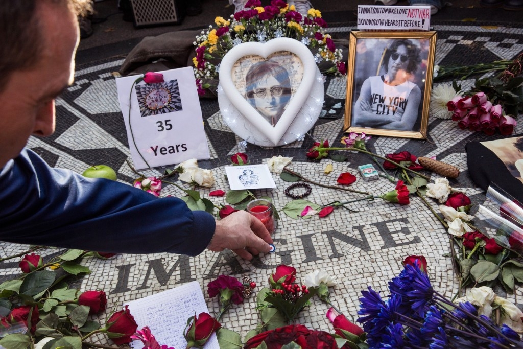 A man places a pin a top the 'Strawberry Fields' tile mosaic in Central Park to mark the 35-year anniversary of John Lennon's death.