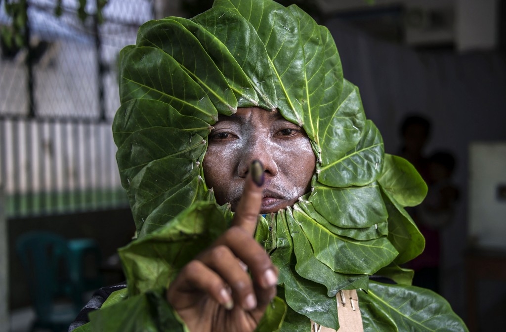 An Indonesian man dressed as a plant to increase peoples' awareness of the environment shows his inked finger after voting in the country's  first nationwide regional elections.