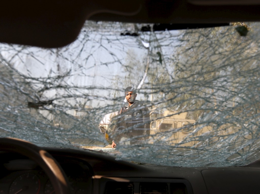 An Afghan man is seen through the cracked window of a vehicle at the site of a suicide attack in Surkhrod, Afghanistan