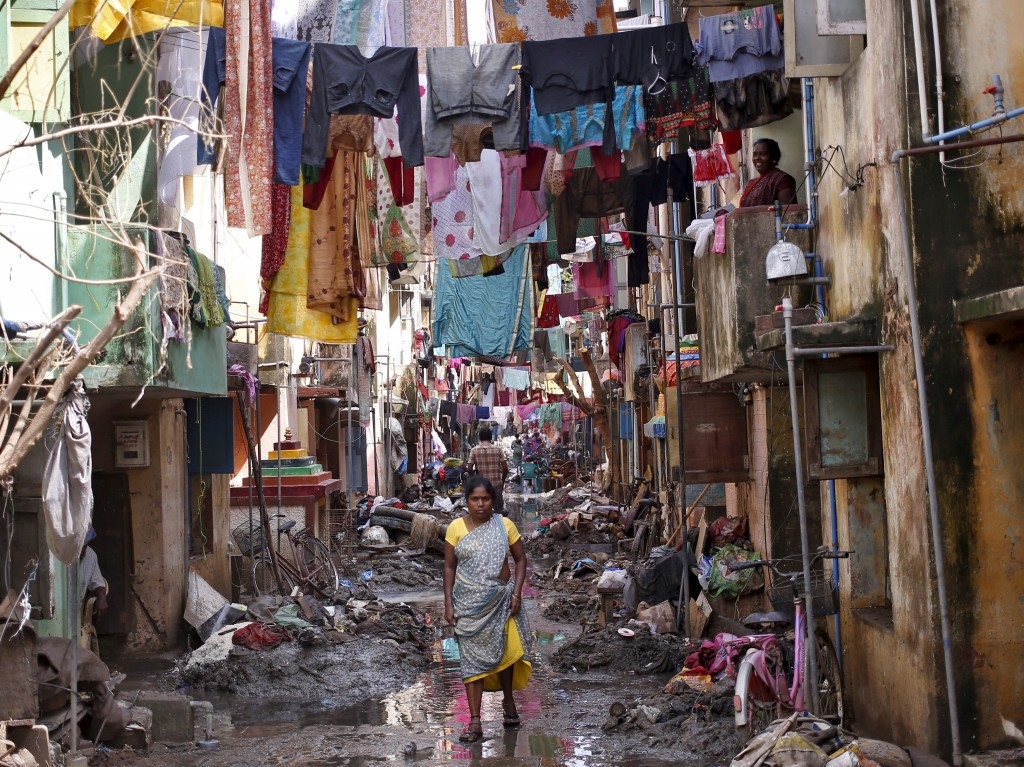 A woman walks in an alley filled with mud and debris to collect food after flood waters receded in Chennai, India.