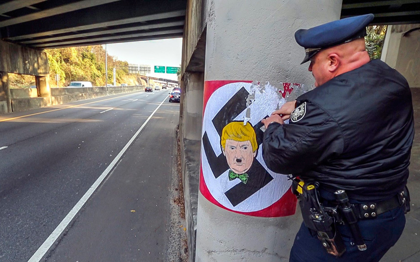 Cop removing Adolf Trump sticker