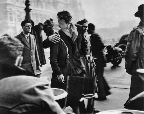 The Kiss by the Hôtel de Ville (1950)...We've all seen Robert Doisneau's black-and-white photograph of a couple swept up in a spontaneous kiss. Paris City Hall forms the backdrop behind them. A man sits at a cafe in front. Pedestrians on the sidewalk clip by indifferently. But the couple is stopped in time, entirely consumed, and completely consuming. Taken on April 1, 1950, The Kiss by the Hôtel de Ville is the image that captures and projects Paris as a city of romance. But how spontaneous was it?We may have never known if it wasn't for the legal pursuits of a couple of elderly women in 1988. During that year, the French magazine Telerama put the image on its cover, prompting several women to claim they were the girl in the photo. Two of them sued. One claimed that, in taking the photograph, Doisneau had violated her privacy. She sought $18,000 in damages. The other, Françoise Delbart, wanted royalties.Doisneau had to come clean. He admitted the woman in the photo was Delbart and that he had staged the shot.