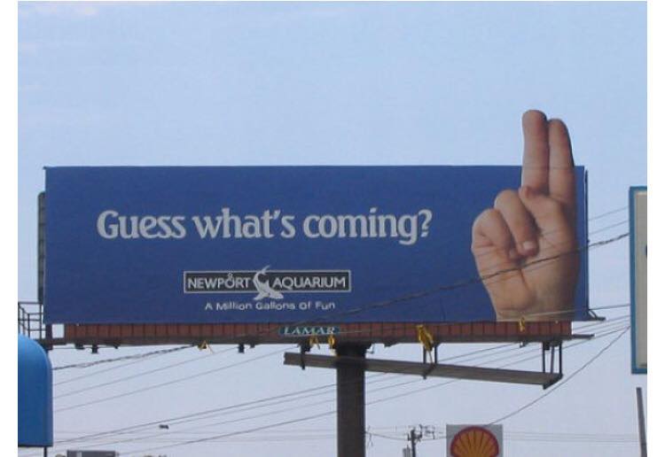 Billboard asking Guess What's Coming with hand holding up two fingers