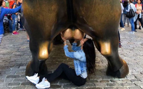 Woman gesturing inappropriately at the bull of Wall Street.