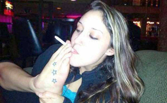 Funny pic of a woman smoking a cigarette with her feet.
