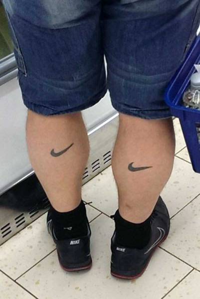 Funny picture of a man wearing Nike sneakers and also has a nike symbol tattooed on each calf.