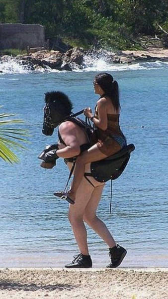 Funny but strange BDSM picture of woman riding a man wearing a mas like he is a horse. Also, he is wearing horse hooves gloves.