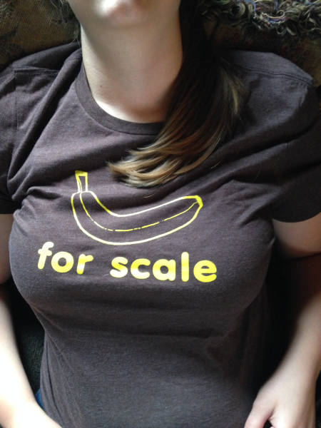 Girl wearing tight 2 shirt to show off her boobs with banana for scale written on the shirt.