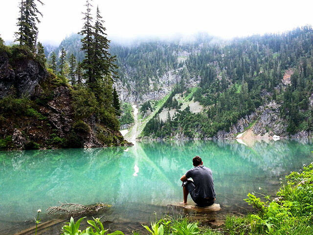 Man sitting by amazingly clear lake.