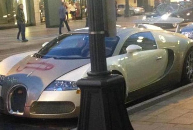 Funny picture of a really hot car, Bugatti, that has some Arabic graffiti scrawled on its front hood.