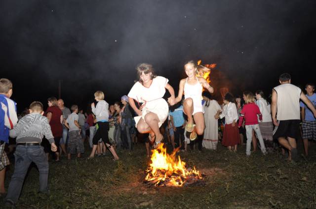 Funny picture of girls jumping over a fire, but one of them has hair burning already.