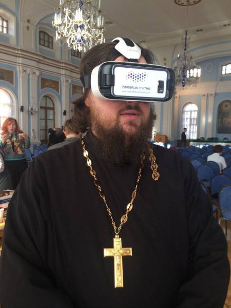 priest with giant gold cross checking out some new Virtual Reality glasses.