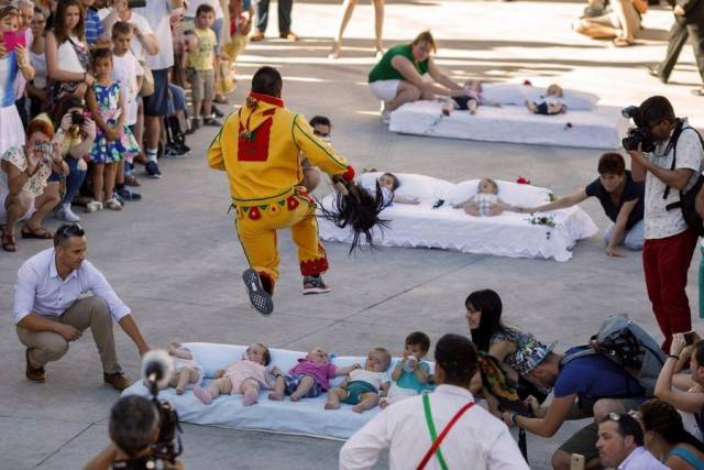 Someone running over rows of kids dressed in costume, probably as part of some ritual.