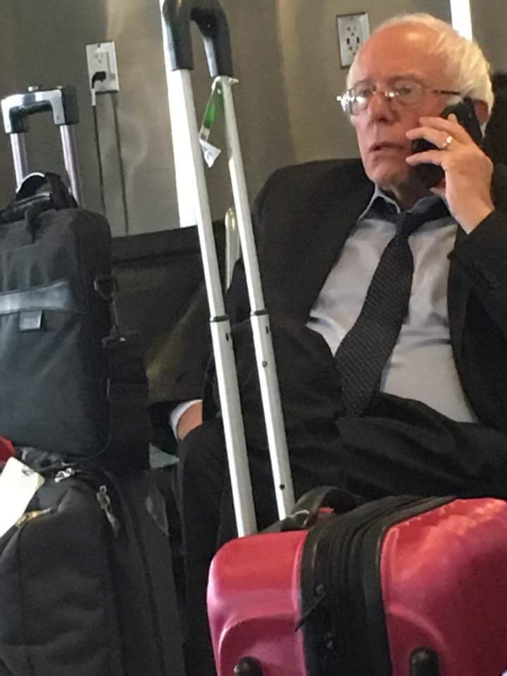 Bernie Sanders making phone calls among a pile of luggage
