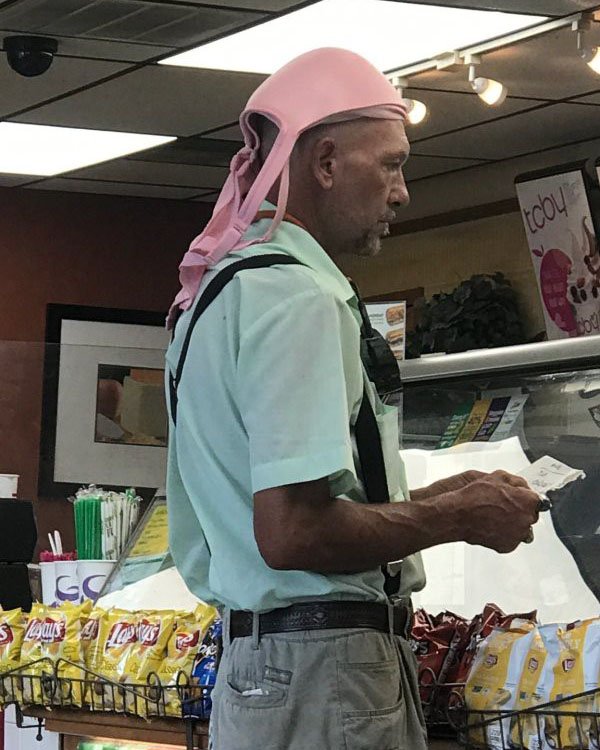 Man wearing a large bra on his head instead of a hat.