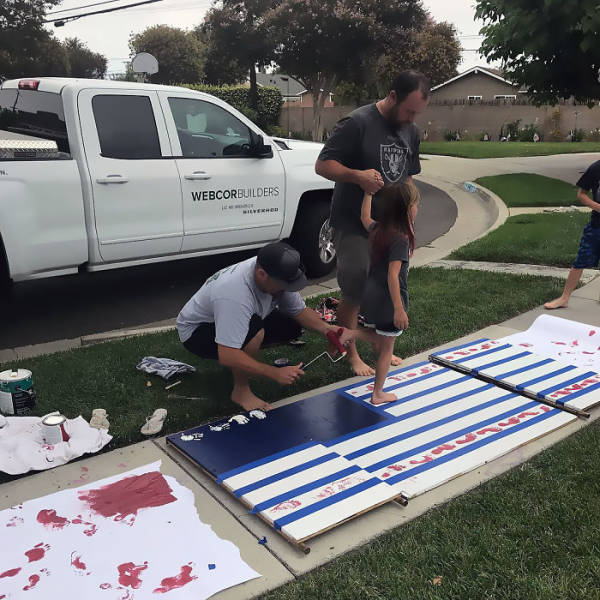 Foot painting flags on the grass, next to large pickup truck.