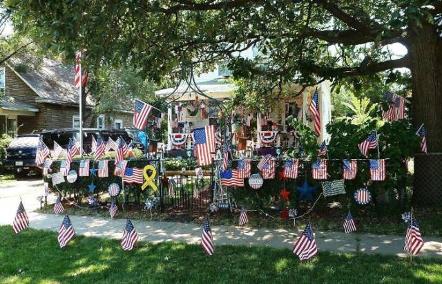 some kind of memorial in front of a house that contains many american flags.