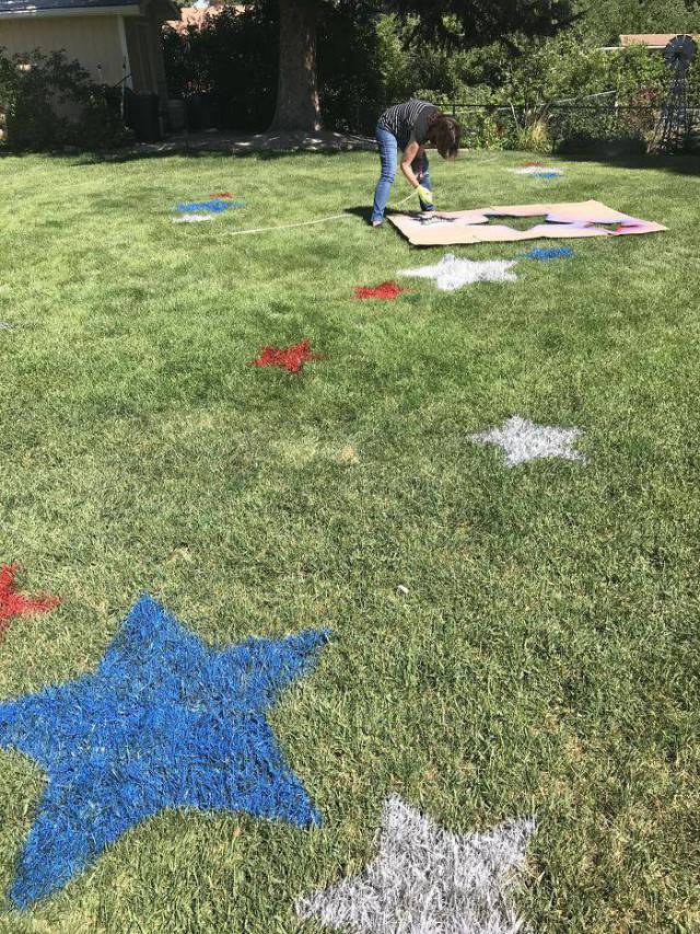 spray painting red, white, and blue stars on the grass.