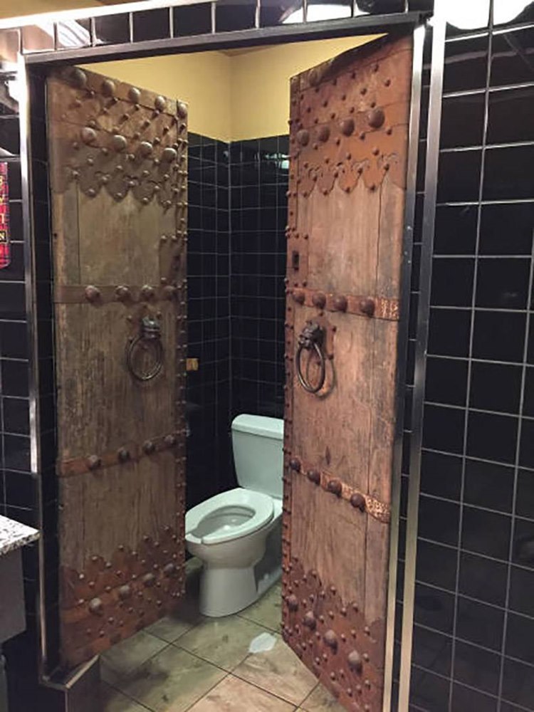 Old school dungeon looking door to a bathroom stall
