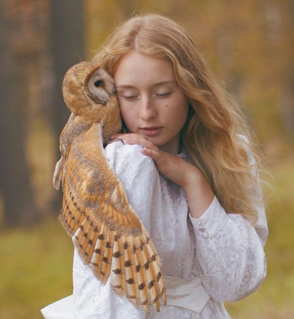 Red haired girl in a forest with an owl on her shoulder