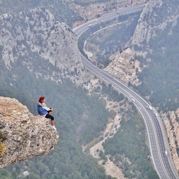 Cool pic of a woman sitting on the edge of a cliff overlooking the mountain pass