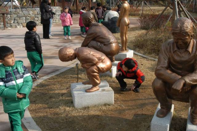 Funny picture of squatting statues and kid checking them out.