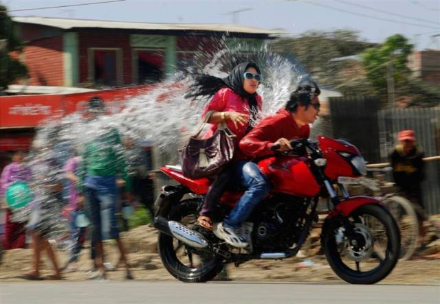 Couple on a motorcycling speeding through a cloud of splashed water