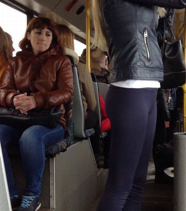 Woman on the bus checking out another woman on the bus with tasty-lip expression.