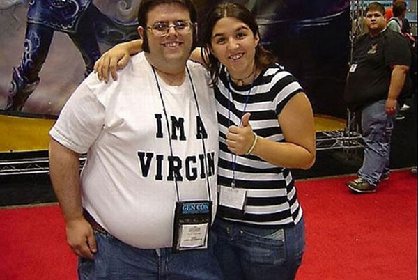 Man with a I Am A Virgin shirt posing for a pic with a girl.