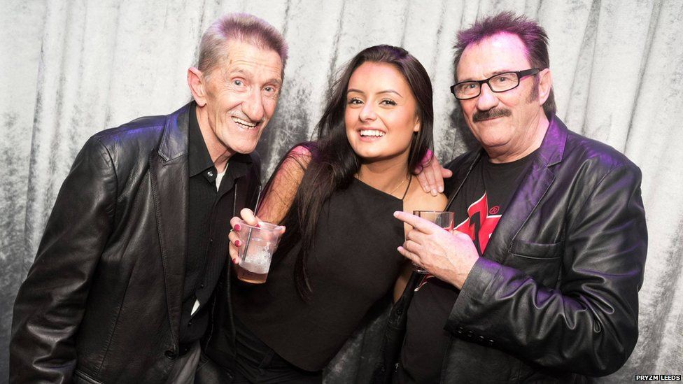 Woman posing with 2 men and her arm and hair make out an obvious penis
