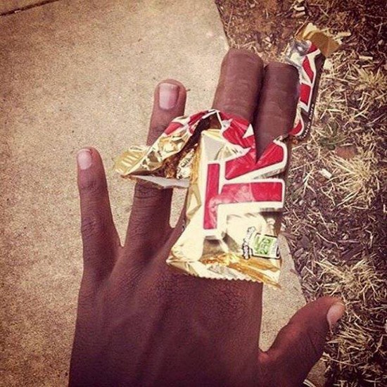 Awesome optical illusion of a black man holding opened Twix bar that looks like his fingers