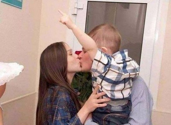 Couple kissing with kid in the foreground that causes an optical illusion
