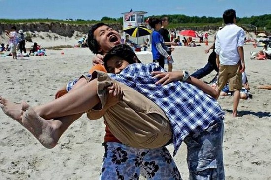 3 men hugging on the beach that is an optical illusion of 2 men hugging out of whack