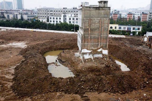 The Tenant Of This Apartment Building In Kunming, China, Has To Cross A Moat After The Contractors Dug A Ditch To Force The Last Family Out.